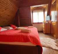 A room with wooden walls, a red bed, and a floor with a wooden decor in a hotel and guesthouses.