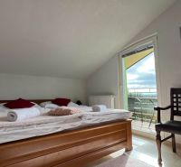 Attic room in hotels and guesthouses with a bed and a balcony, floor with wooden decor.