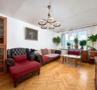 Living room in a two-room apartment with a wooden decor floor and comfortable seating.