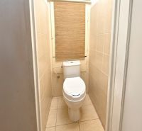 A toilet with light tiles in a 2-room apartment.