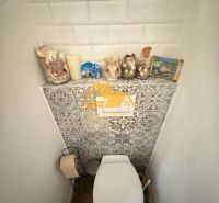 A toilet with decorations and a wooden decor floor in a family house.