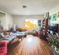 Living room of a family house with Buddha decorations, a sofa bed, and a wooden-patterned floor.
