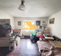 A room in a family house with a wooden decor floor, furnished with a sofa and decorations.