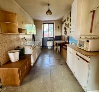A kitchen in a family house with a long countertop, a dining table, and wall decorations.