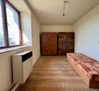 The interior of a family house with a sofa, a wardrobe, and a window.