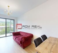 Bright living space with a red sofa, dining table, and a view of the balcony.