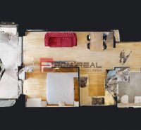 Floor plan of a 2-room apartment with wood-patterned flooring and a red sofa.