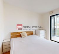 A bedroom in a 2-room apartment with a bed, two dressers, and access to a balcony.