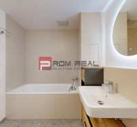 Bathroom in a 2-room apartment with a bathtub, sink, and illuminated mirror.