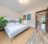 A bright bedroom with a plant, wooden floor decor, and art on the wall in a 3-room apartment.