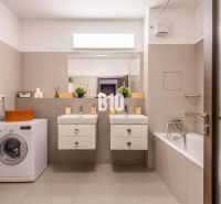 A bathroom in a 3-room apartment with two sinks and a washing machine.