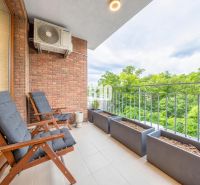The balcony of a 3-room apartment on Ďumbierska Street in Bratislava III with comfortable seating and greenery.