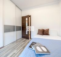 A bedroom in a 3-room apartment with a wood-patterned floor, a built-in wardrobe, and a bed with pillows.