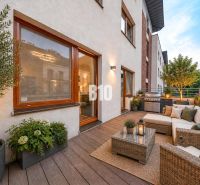 Terrace of a 3-room apartment with seating, plants, and a grill, floor with wooden decor.