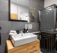 A bathroom in a 3-room apartment with a stylish sink, washing machine, and dryer.