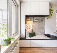 A bright interior of a 3-room apartment with a cozy reading nook and a floor with a wooden decor.