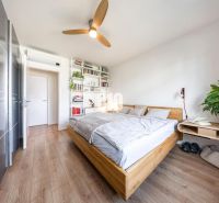 A bright bedroom in a three-room apartment with a wood-decor floor and modern furniture.