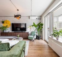 Living room in a 3-room apartment with a wooden decor floor and lots of plants.