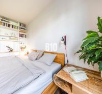 A cozy bedroom with a bookshelf, plants, and wooden furniture in a 3-room apartment.