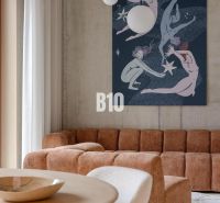 A bright living room with a sofa, striking art, and pendant lights in a two-room apartment.