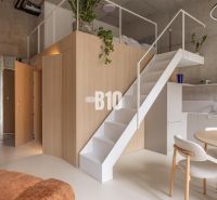 Interior of a 2-room apartment with a loft structure, a sofa set, and a floor with a wooden decor.