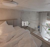 Loft bedroom with a concrete ceiling in a 2-room apartment, with white bed linen.