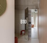 A hallway in a 2-room apartment with a concrete wall and mirrored doors.