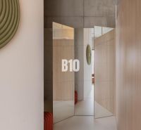 Mirror wall and wooden decorations in a 2-room apartment with a concrete ceiling.