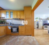 A kitchen in a 3-room apartment with a wooden decor floor and light furniture.