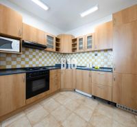 A kitchen with wooden cabinets and tiles in a 3-room apartment.