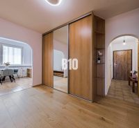 Interior of a 3-room apartment with a wooden decor floor, mirrored wardrobe, and dining area.