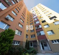Apartment building in Bratislava V with an orange-yellow facade and greenery at the entrance.