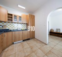 A kitchen with wooden cabinets and light tiles in a three-room apartment.