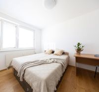 A bedroom in a 3-room apartment with a bed, table, and floor with a wooden decor.