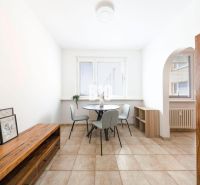 Dining area with a table and chairs in a 3-room apartment, tiled floor.