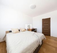 A bedroom with a wooden decor floor in a 3-room apartment, simple furniture and a bed.