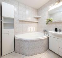 A bathroom with a bathtub, sink, and cabinets in a 3-room apartment with white tiles.