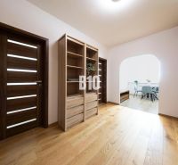 A hallway of a 3-room apartment with a shelving cabinet and a floor with a wooden decor.