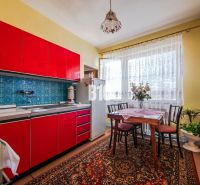 A kitchen in a family house with bright red cabinets and blue tiles.