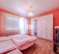 Bedroom with pink walls, a wardrobe, a bed, and a wooden decor floor in a family house.