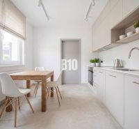 A kitchen in a 3-room apartment with a wooden decor floor and a wooden table.