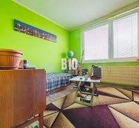 A room in a 3-room apartment with a colorful carpet and green walls, wooden furniture.
