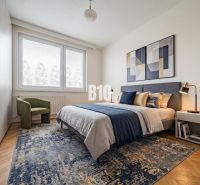 A bedroom in a three-room apartment with carpets, a bed, and a chair on a floor with a wooden decor.