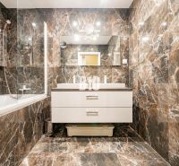 Elegant bathroom with marble tiles and a bathtub in a 3-room apartment.