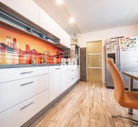 Kitchen in a 3-room apartment with a wooden decor floor and colorful wall wallpaper.