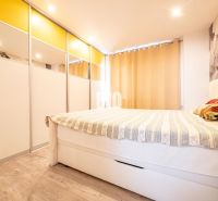 A bedroom in a three-room apartment with a wooden decor floor and a built-in wardrobe.