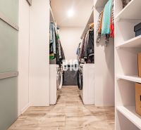 Wardrobe with a washing machine in a 3-room apartment, floor with wood decor, shelves and clothes.