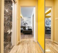 A hallway in a 3-room apartment with a wooden decor floor and yellow walls.