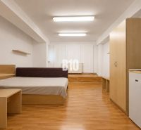A bedroom in a two-room apartment with a wooden decor floor and simple furniture.