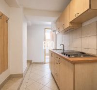 A kitchen with tiles and wooden cabinets in a two-room apartment.